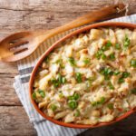 Portuguese food: casserole with cod, potatoes, onions and cream in a baking dish close-up on the table. horizontal top view from above